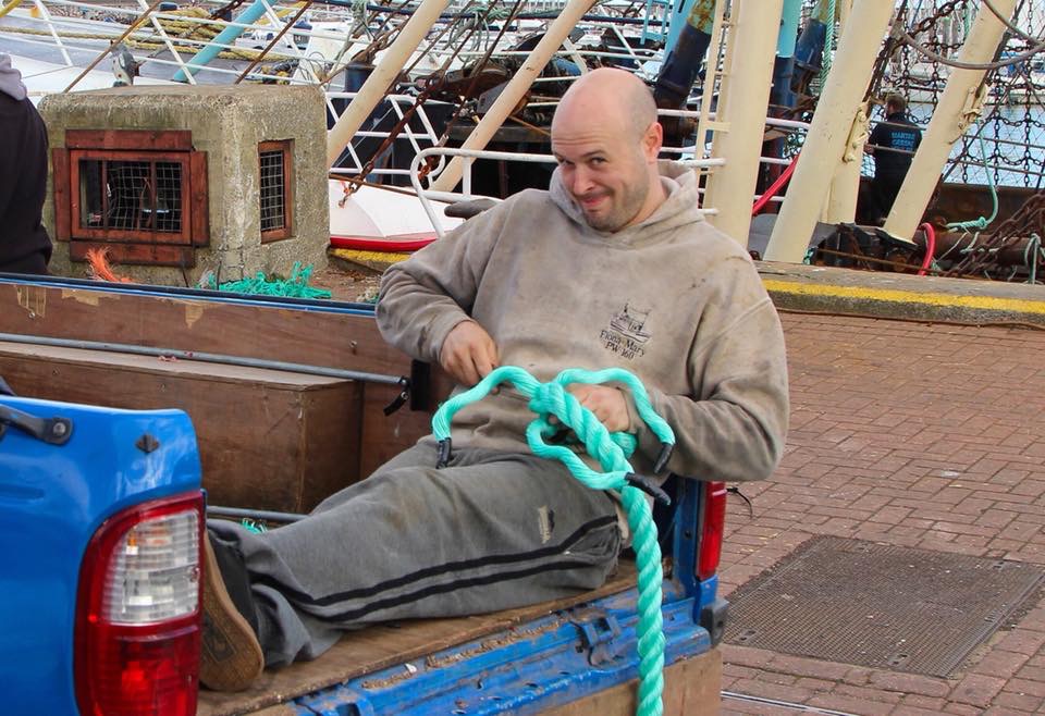 Crew member mending rope quayside