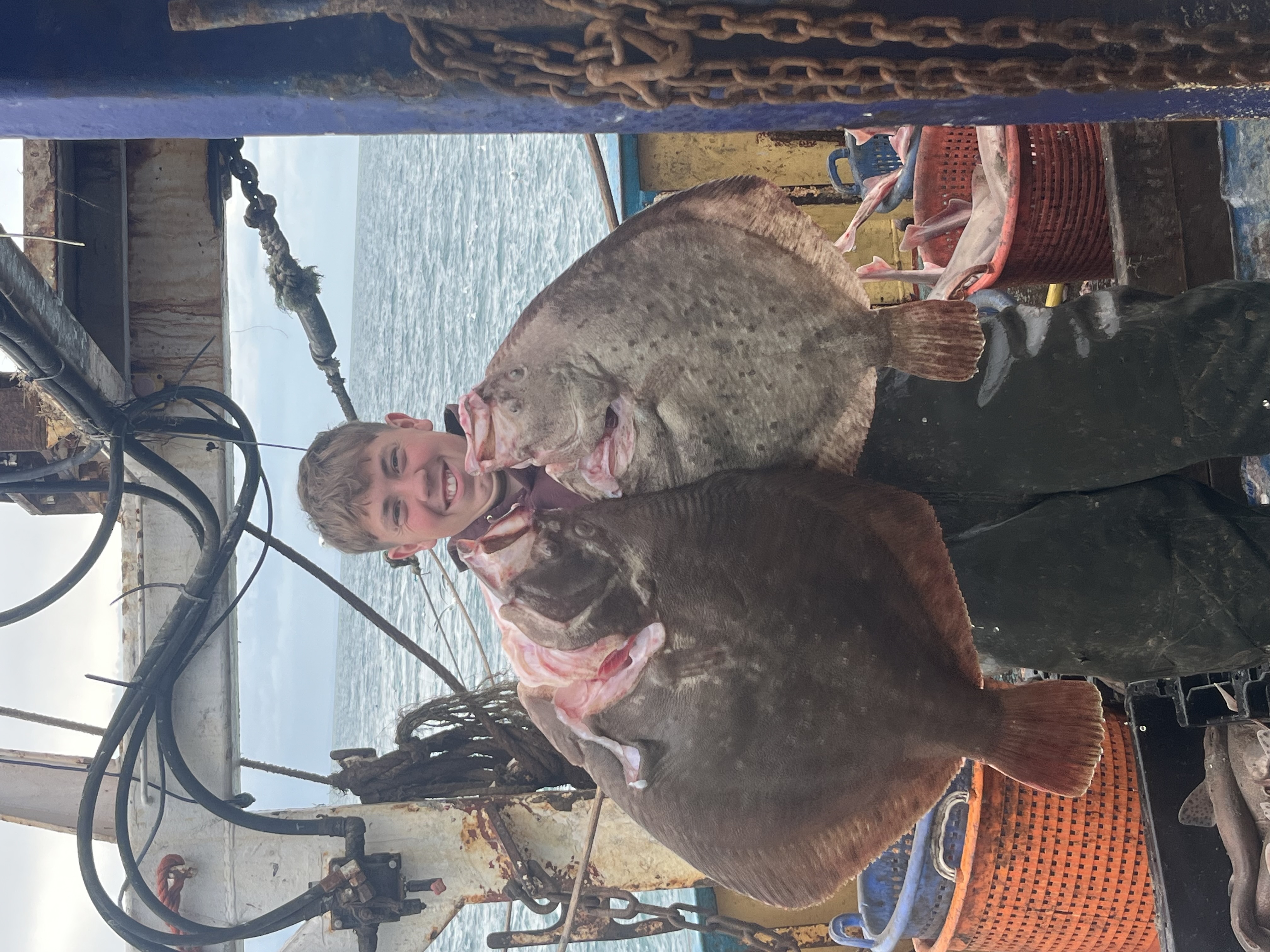 Proud young fisherman holding two big turbot
